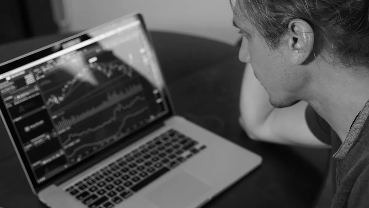 Man studying investment data on a laptop screen, researching before making gold allocation decisions