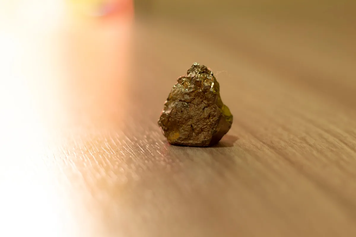 A naturally occurring mineral specimen on a wooden surface, illustrating the geological origins of gold before human refinement