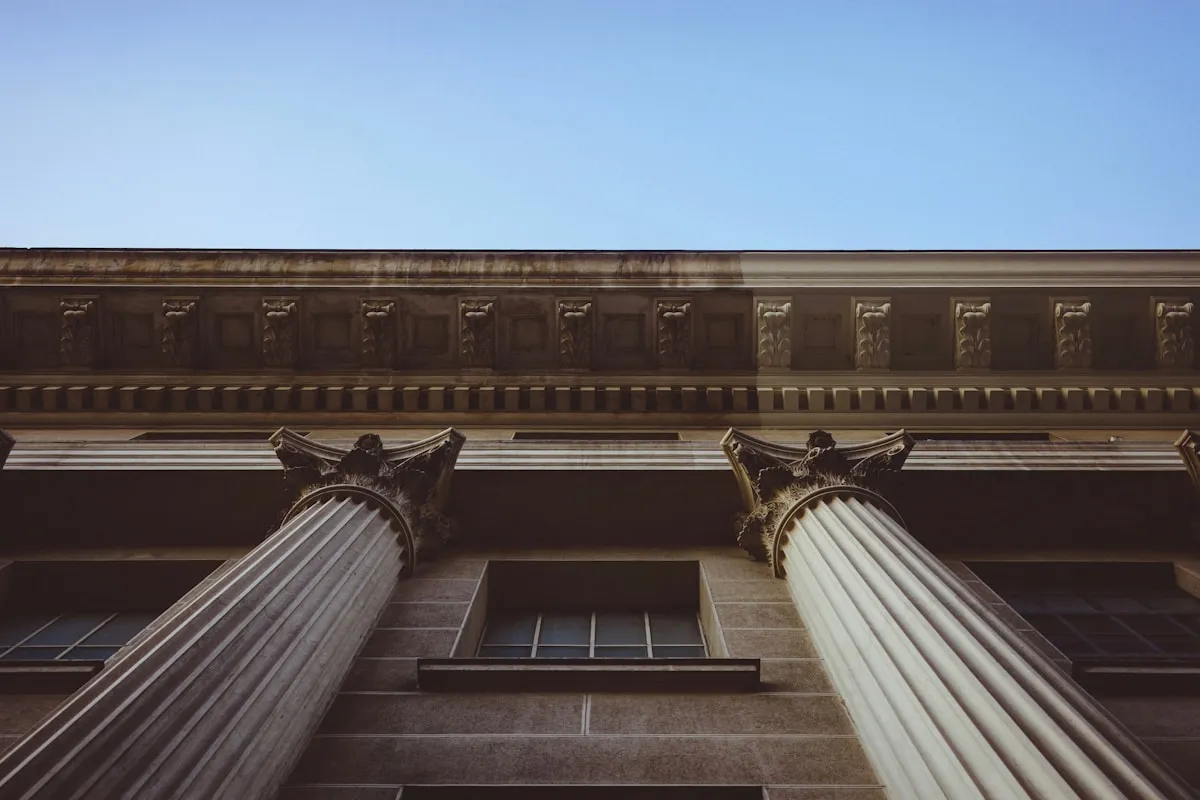 Tall building with classical columns against the sky representing the towering influence of central bank rate decisions on gold