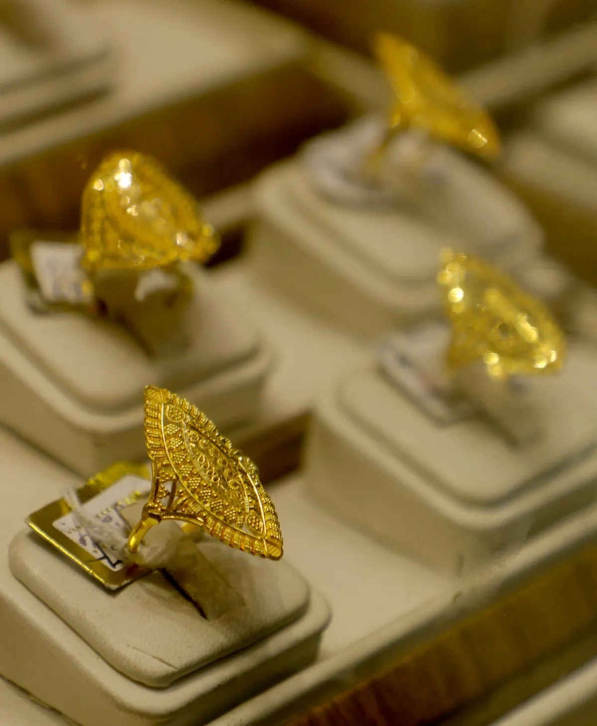 Ornate gold rings displayed on stands, showcasing the variety of colors and finishes achievable through different gold alloy compositions