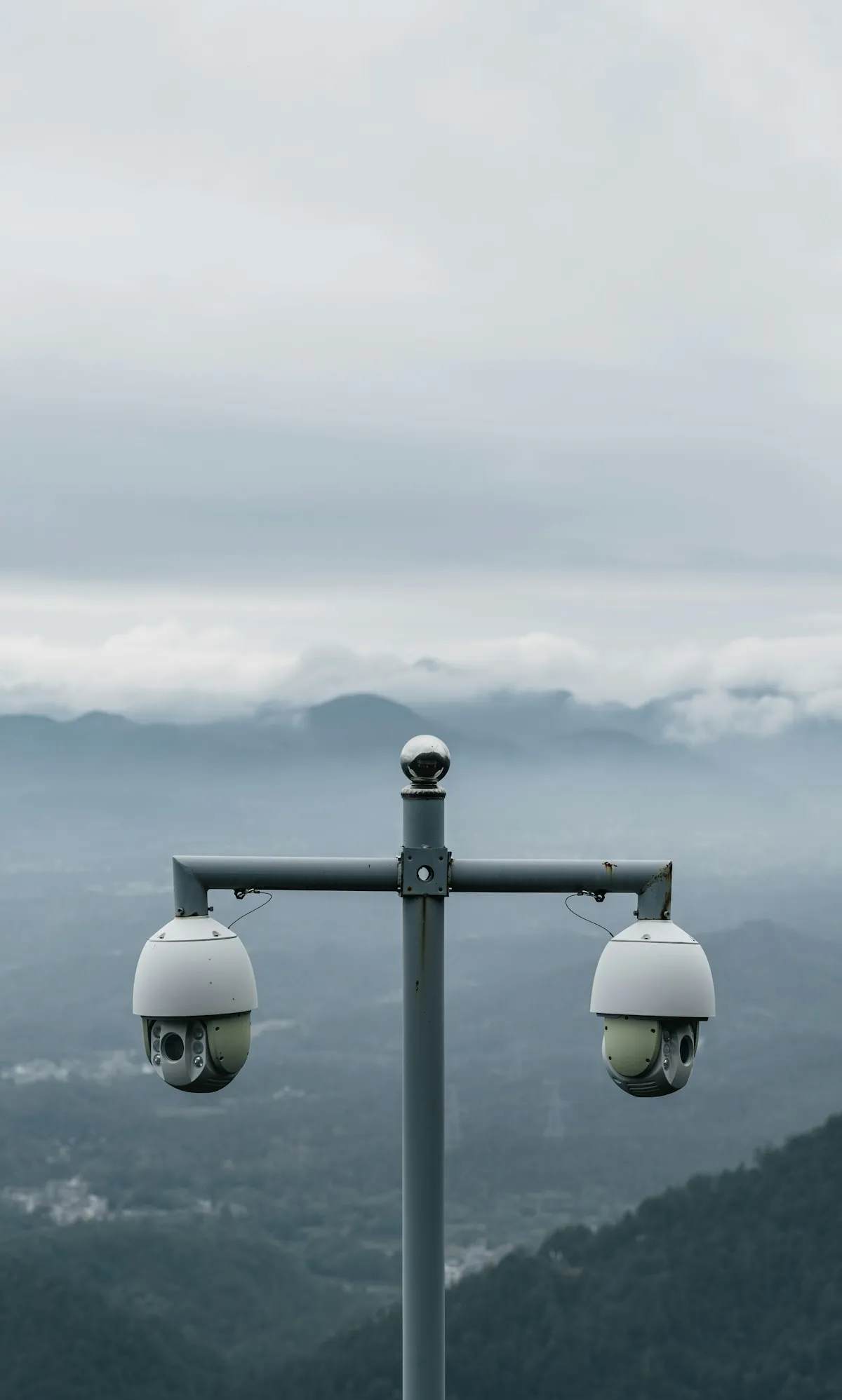 Two surveillance cameras overlooking a mountain landscape, constant vigilance over your information exposure is as important as physical security measures