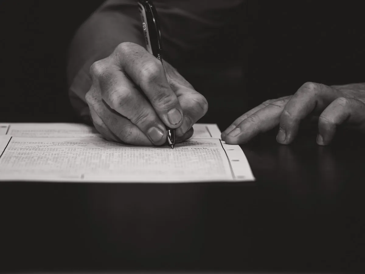 A hand writing with a fountain pen on paper, meticulous record-keeping and documentation form the foundation of legal compliance for precious metals owners