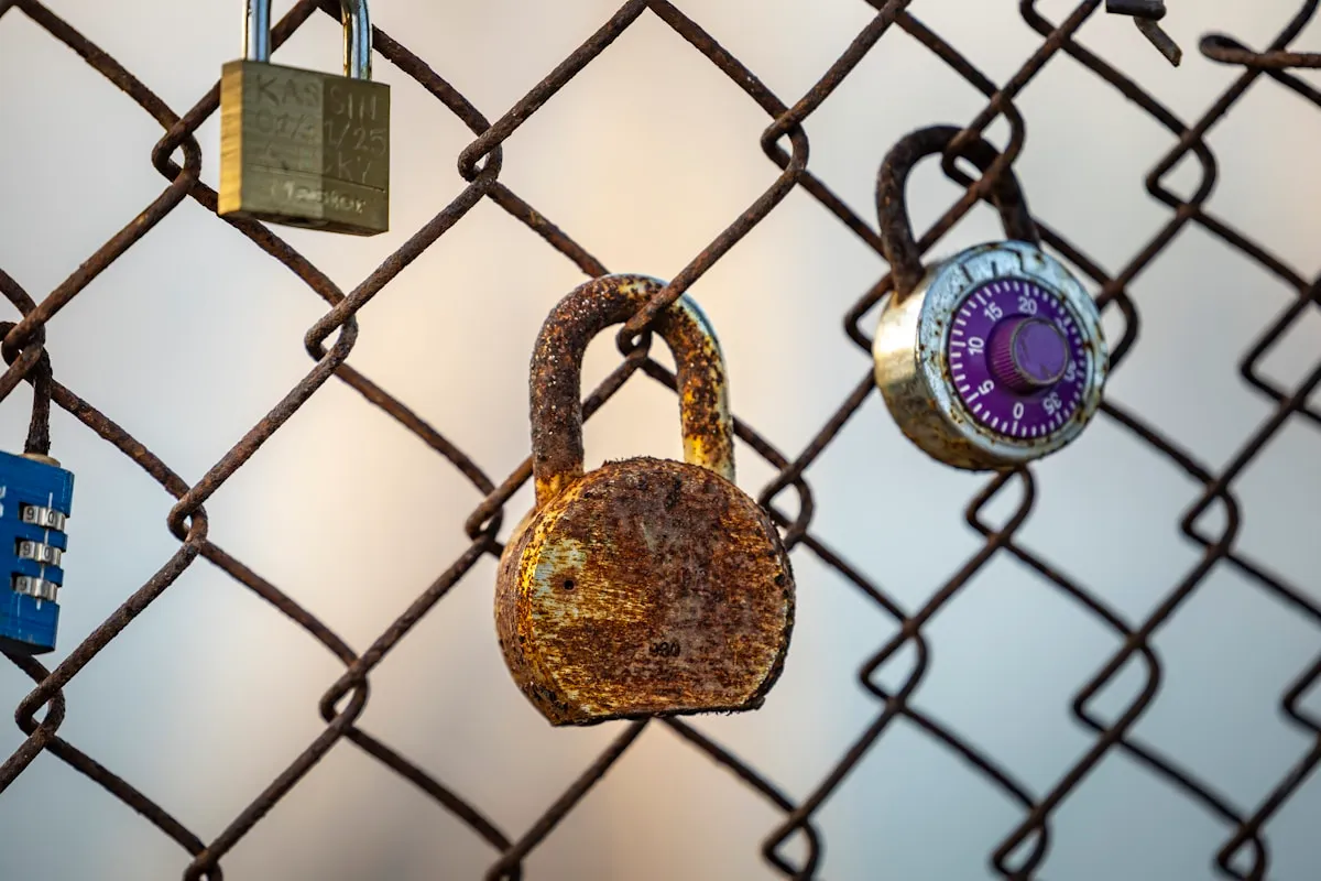 Padlocks on a chain-link fence, representing the multiple layers of coverage needed to adequately protect precious metals across different storage locations
