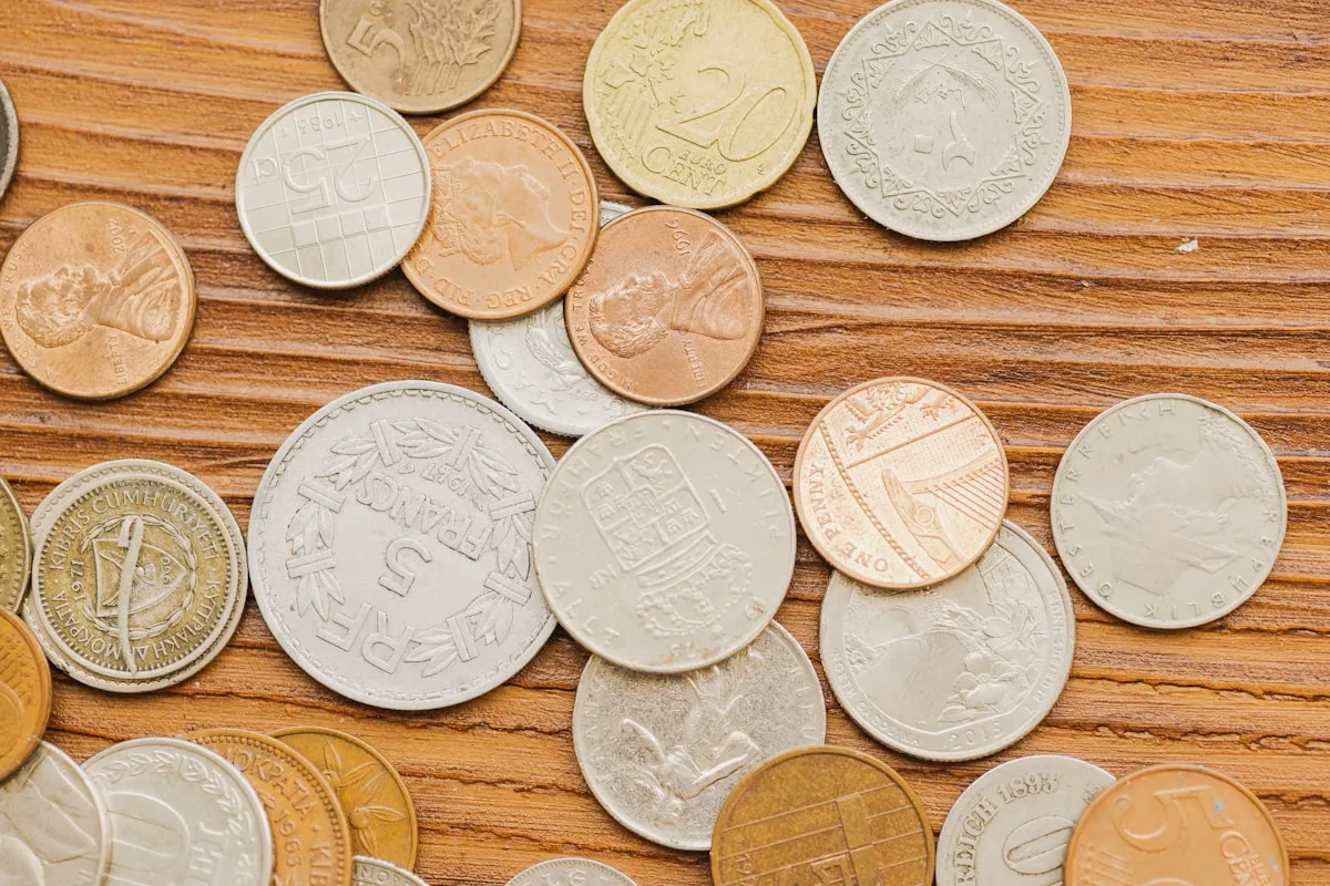 A collection of gold and silver coins on a wooden surface, representing the variety of physical gold investment options